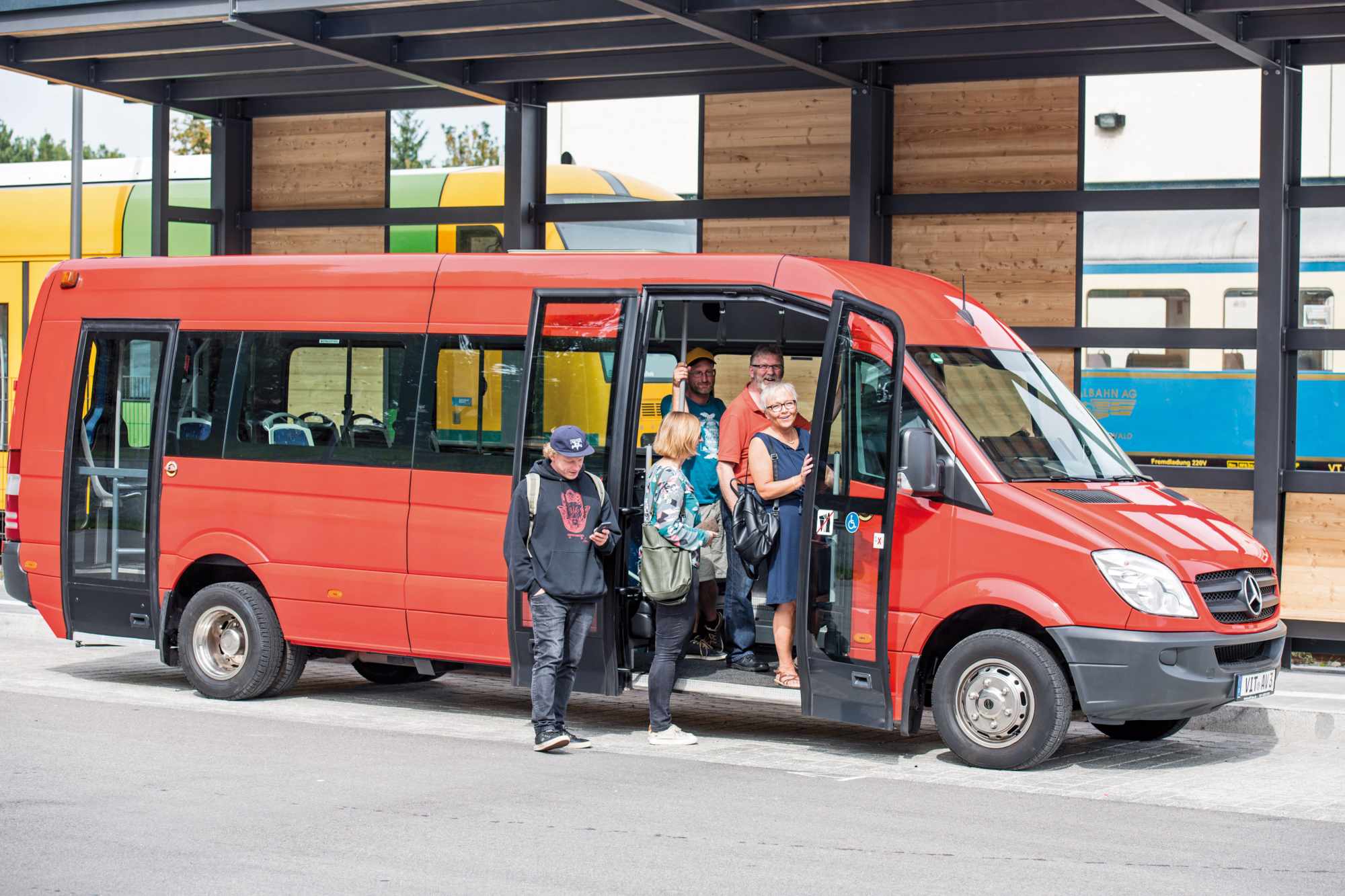 eine Gruppe von Menschen, die vor einem roten Bus stehen